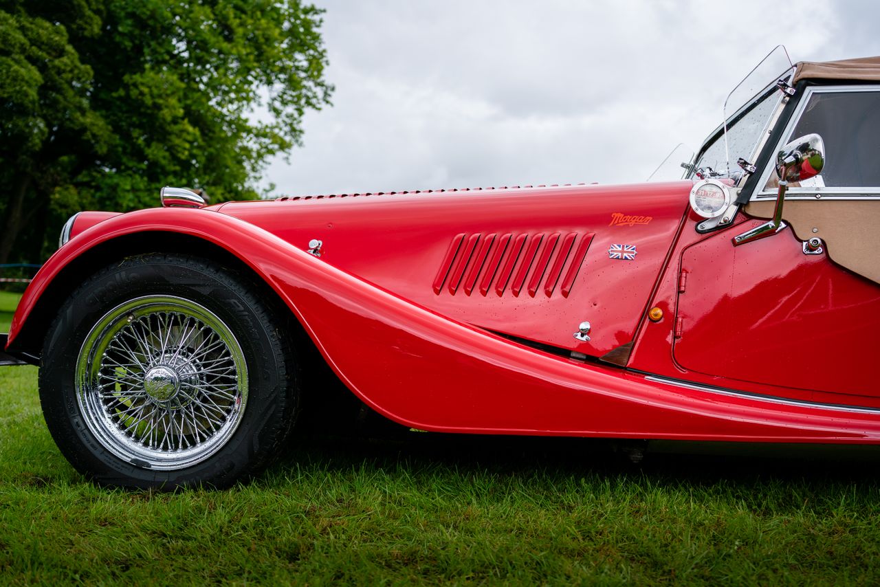capture of a vintage red morgan car with british flag emblem showcasin