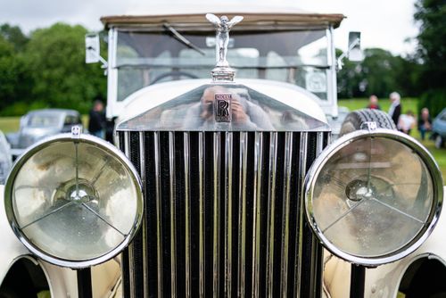 Free Front view of a vintage Rolls Royce showcasing its iconic grille and chrome headlights in a grassy outdoor setting. Stock Photo