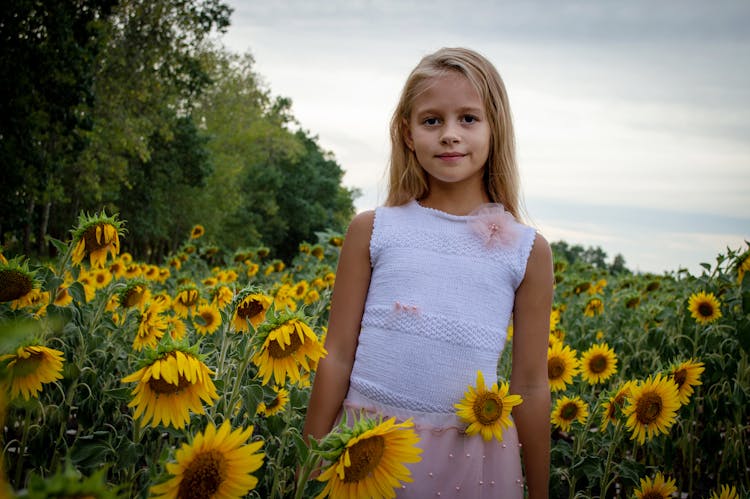 Girl In White Top Standing On The Field Of Sunflowers