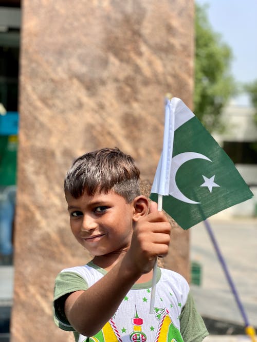 Free A Young Boy Smiling while Holding a Flag Stock Photo