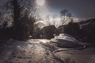 一艘船停在冰封的河面上，阳光明媚，积雪覆盖，四周环绕着冬日景色