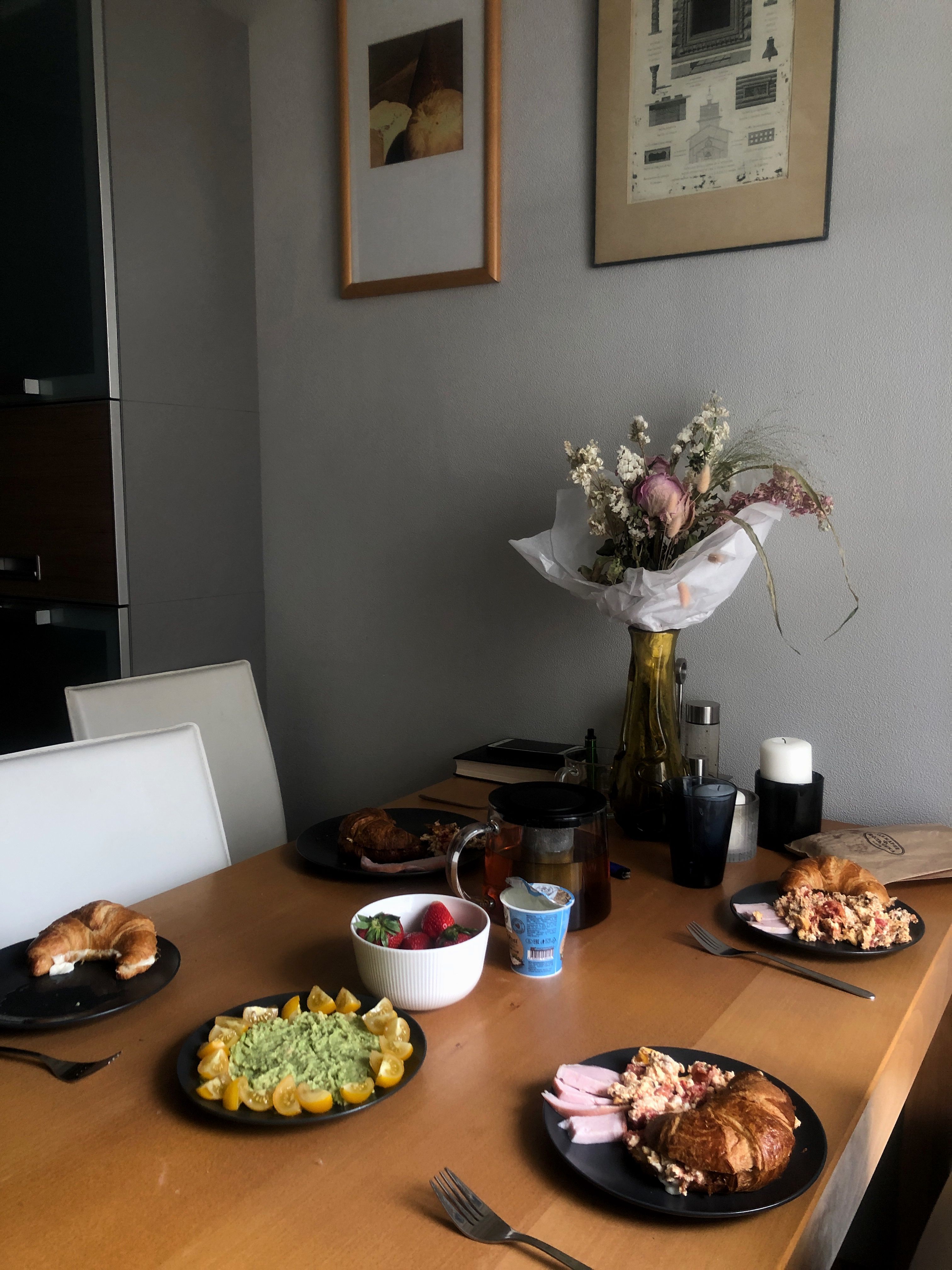 Charming brunch setup featuring croissants, fresh fruit, and a floral centerpiece on a wooden table, perfect for a cozy dining experience.