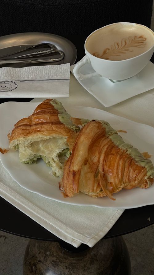 Free Enjoying a croissant and cappuccino at a cozy cafe with a serene ambiance. Stock Photo