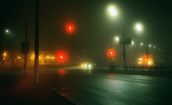 A foggy nighttime city intersection in Moscow with glowing street and traffic lights casting an eerie ambiance.