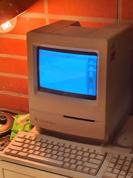 A vintage Macintosh computer with a keyboard under warm indoor lighting, showcasing classic design.