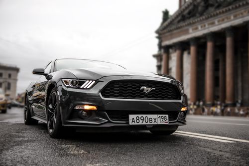 Free A sleek black Ford Mustang parked on a city street, embodying luxury and performance. Stock Photo