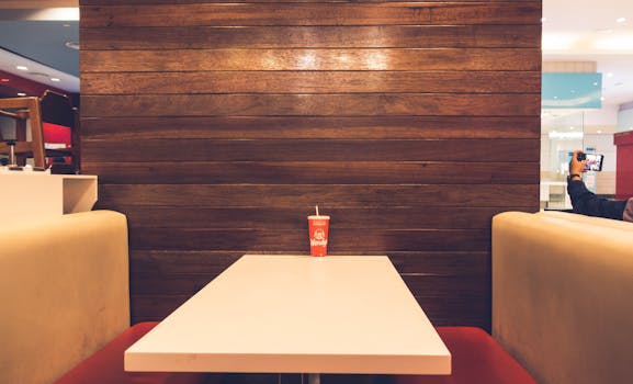 Empty dining booth with wooden decor and a single drink on the table.