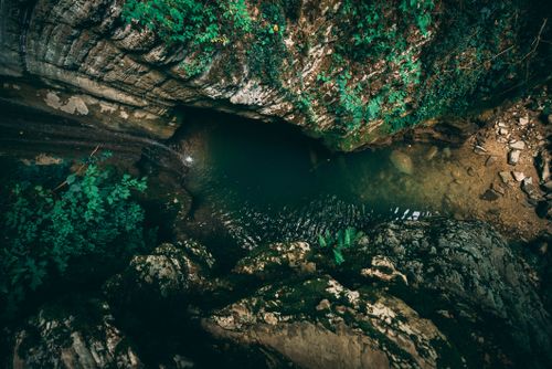 Free Stunning aerial view capturing the rugged terrain and serene waterfall surrounded by lush greenery. Stock Photo