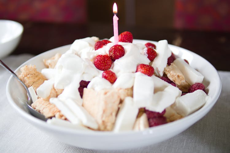 A White Ceramic Bowl With Strawberries And Cream