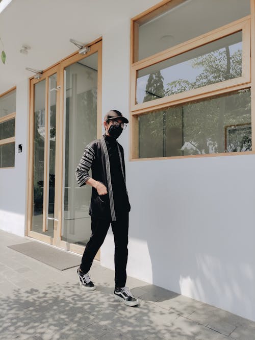 Man Wearing a Black Long Sleeve Shirt Walking on Doorway