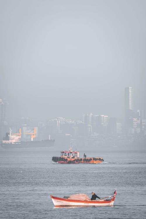 People in Boats on the Coast Near the City 