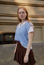 A Woman Wearing a Blue Knitted Vest and Pleated Skirt