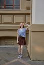 A Woman Wearing a Vest and Skirt Leaning on a Wall
