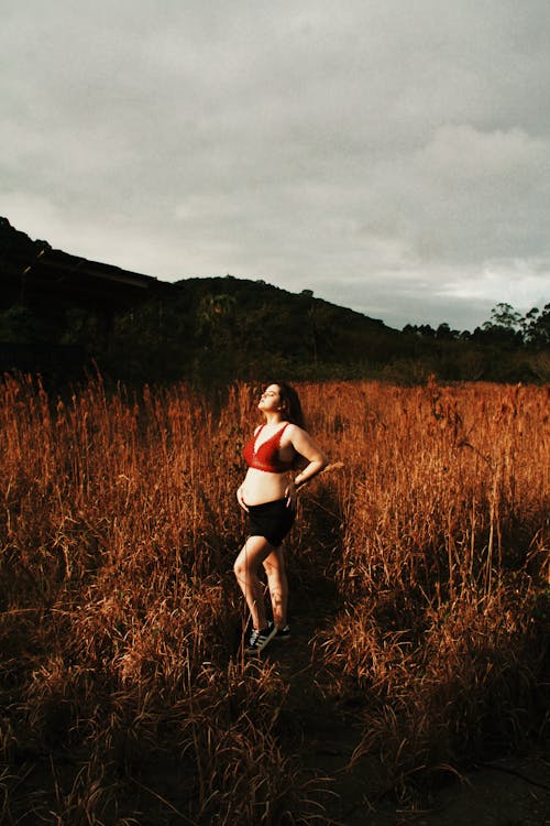 A Pregnant Woman Standing in the Grass Field