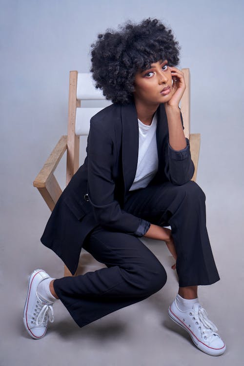 Free A Woman in Black Blazer and Black Pants while Sitting on Wooden Chair Stock Photo
