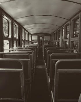 Monochrome view of a vintage bus interior with rows of empty seats.