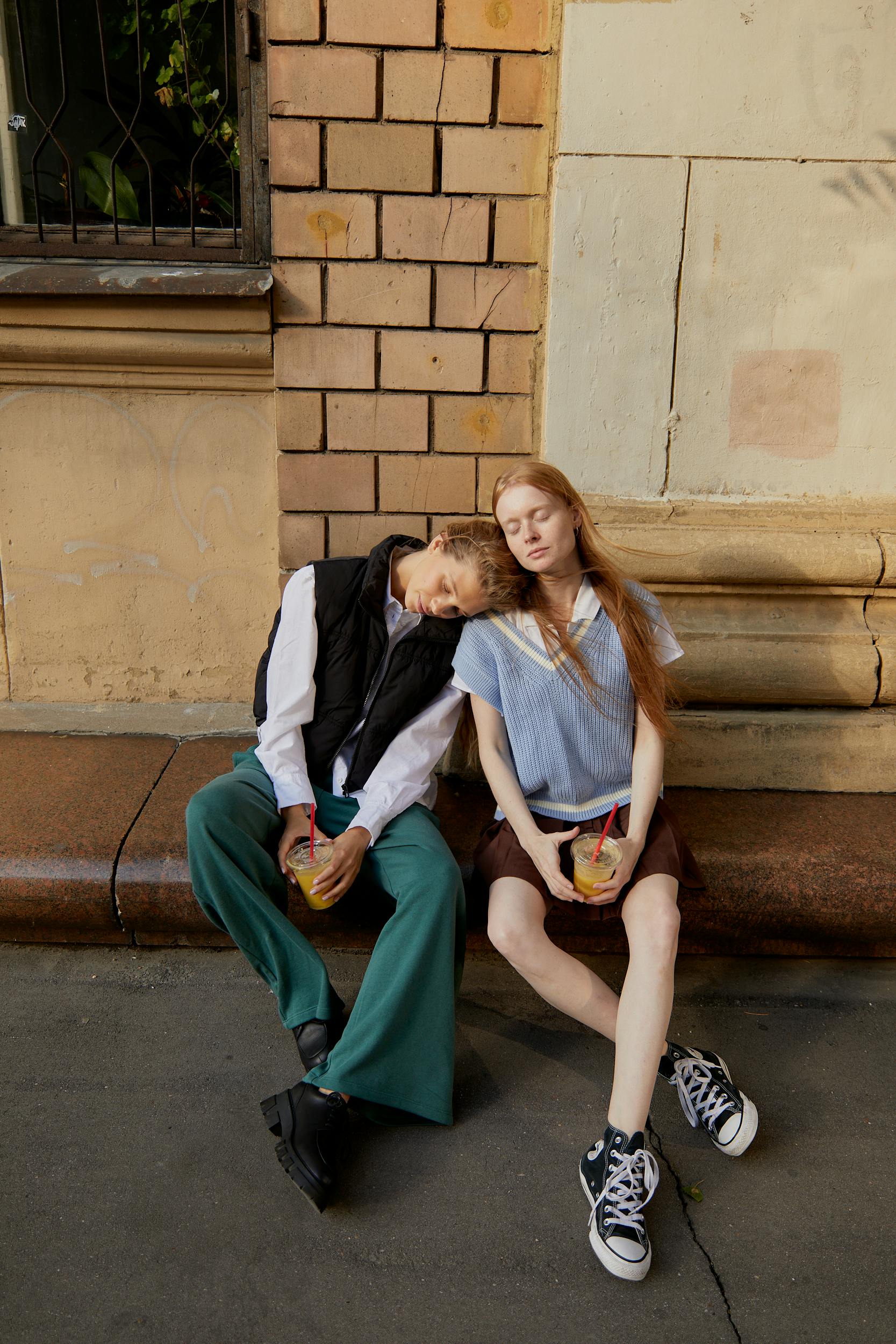 young women sitting on the sidewalk gutter