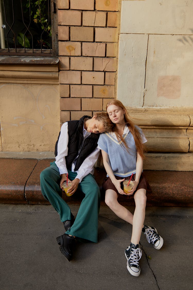 Young Women Sitting On The Sidewalk Gutter