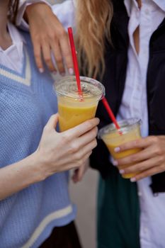 Two students in casual outfits enjoying smoothies outdoors, symbolizing vibrant student life.