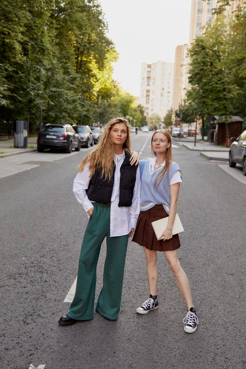 Free Two fashionable women stand confidently on a city road, embodying urban style. Stock Photo