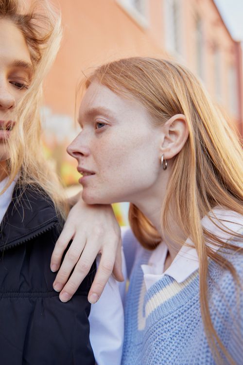 Free Two women with long hair standing outdoors, embodying friendship and style in a vertical shot. Stock Photo