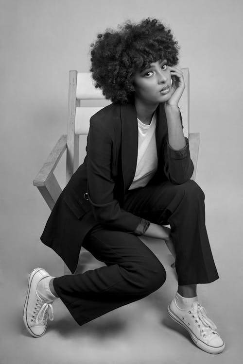 Grayscale Photo of a Woman Sitting on a Chair