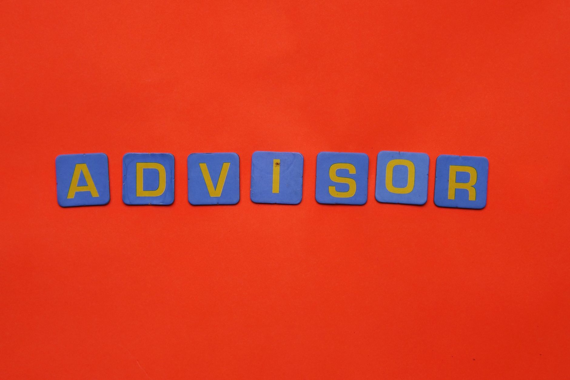 Blue tiles spelling 'advisor' on a striking red backdrop.