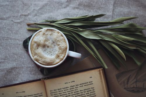 Free A warm cup of coffee with open book and leaves on a table, perfect for a cozy day. Stock Photo