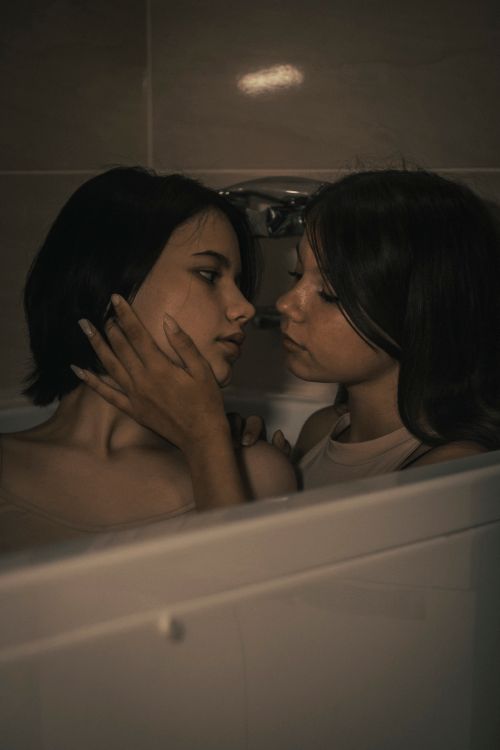 Free Tender moment between two women sharing an intimate embrace in a bathtub at night. Stock Photo