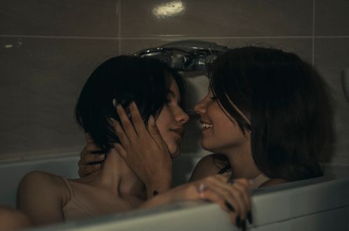 Free A tender moment between two women sharing a loving gaze in a bathtub. Stock Photo