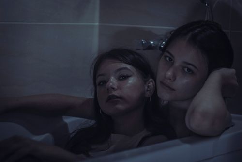 Free Moody portrait of two women in a bathtub, depicting intimacy and togetherness in low light. Stock Photo