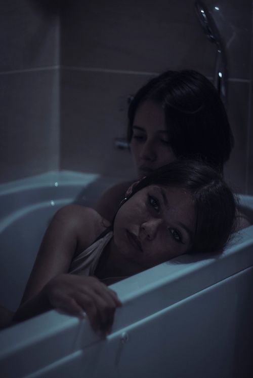 Free A serene and romantic moment shared by two women sitting in a bathtub embracing affectionately. Stock Photo