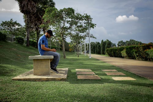 Photo of a Man in a Blue Polo Shirt Sitting on a Concrete Bench