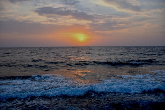 Experience the tranquil beauty of a sunset illuminating the ocean horizon with gentle waves.