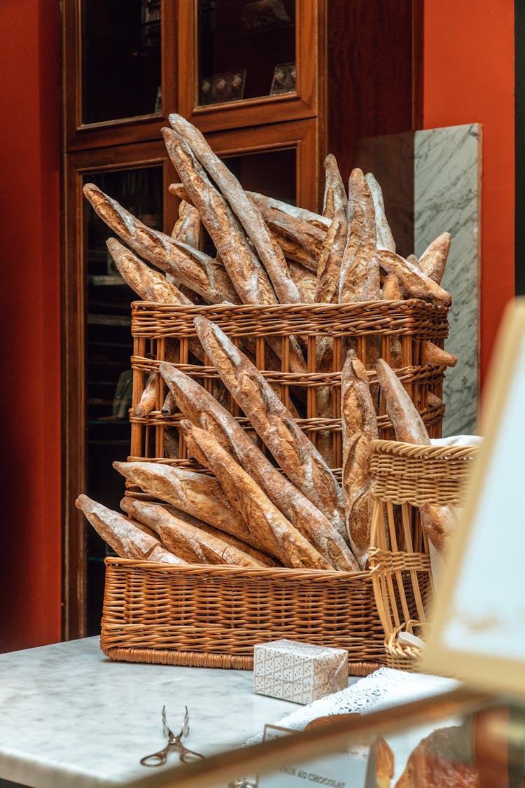 Fresh Baguettes Bread In Wicker Basket On Table Near Bakery