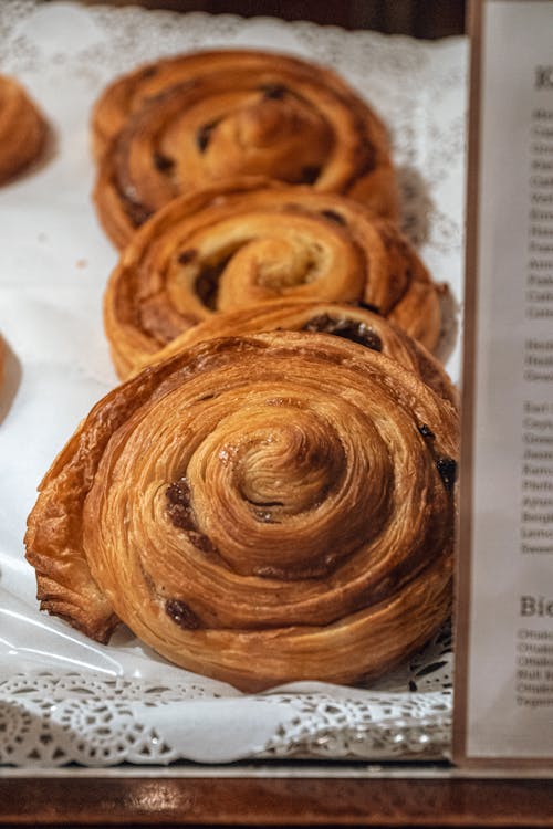 Sweet freshly made crispy buns of puff pastry with raisins placed on white tablecloth