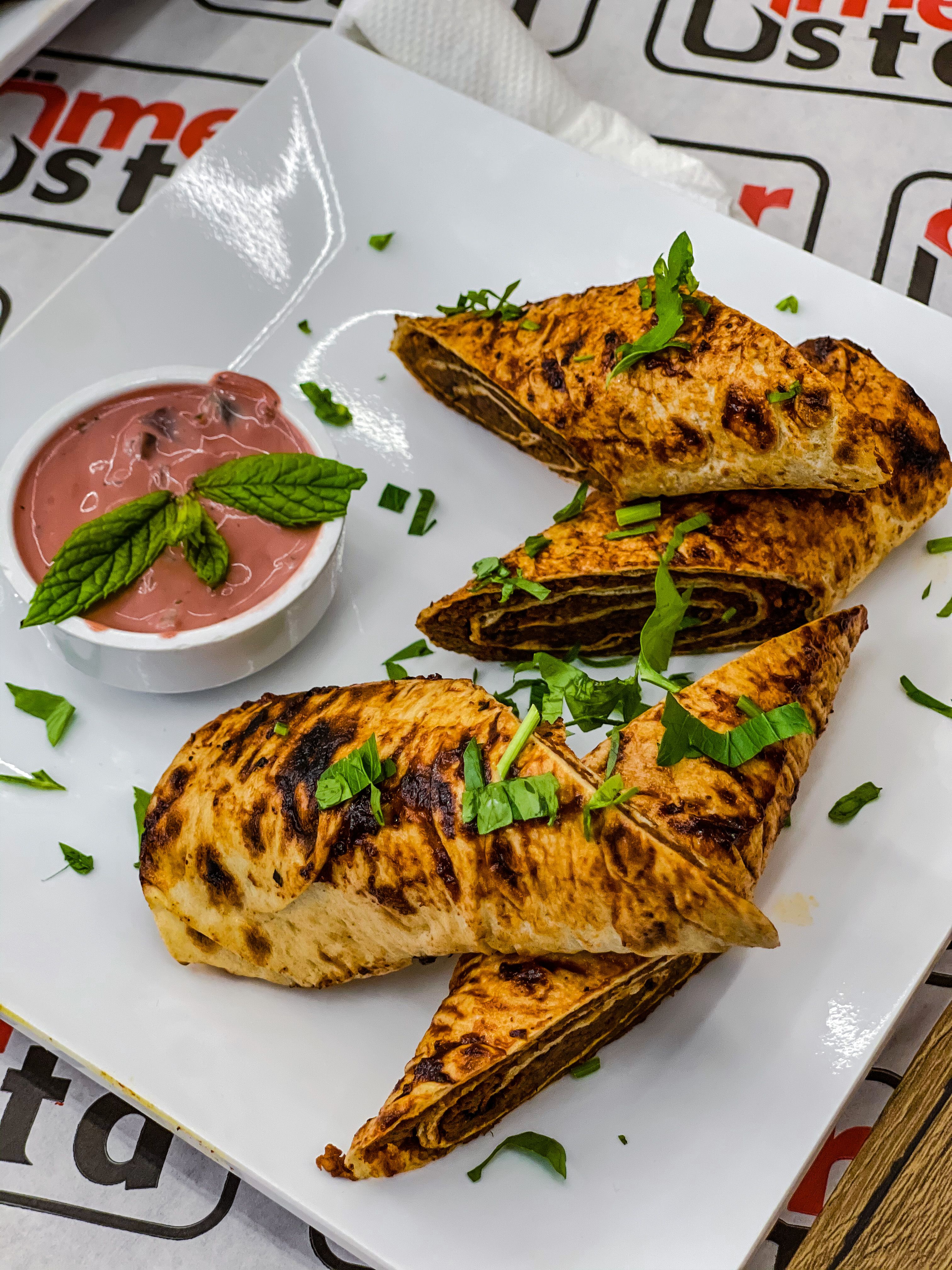 Delicious grilled wraps served with a creamy dip on a white plate.