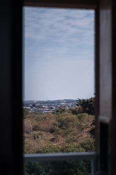 A picturesque view of lush greenery and distant hills framed by an open window.