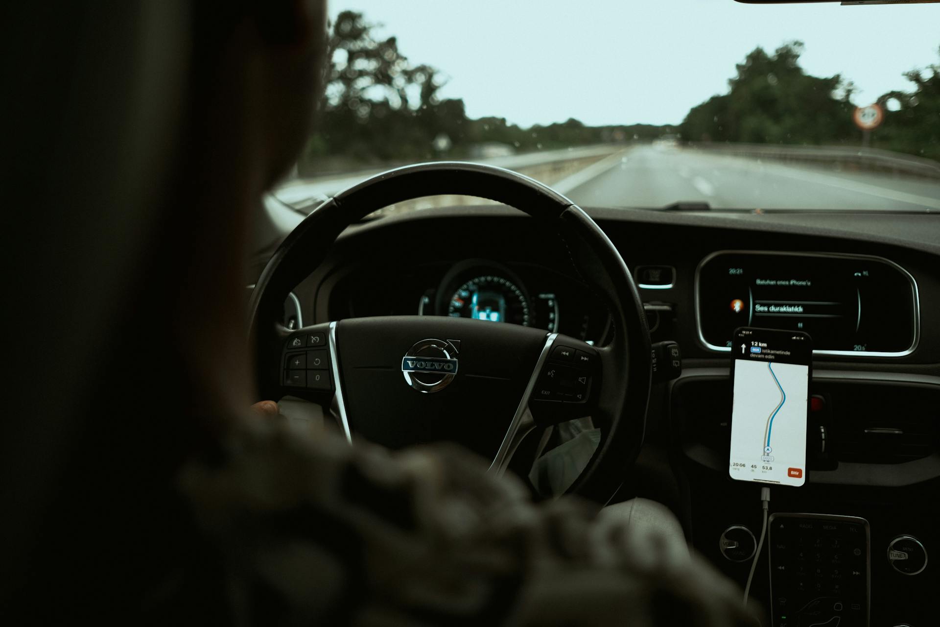 A Person Driving a Car with a Map on Smartphone