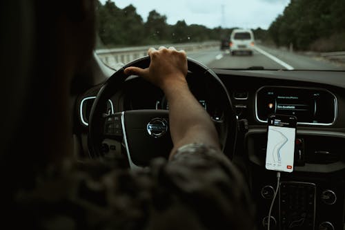 Free Person Driving a Car While Navigating Using Smartphone Stock Photo