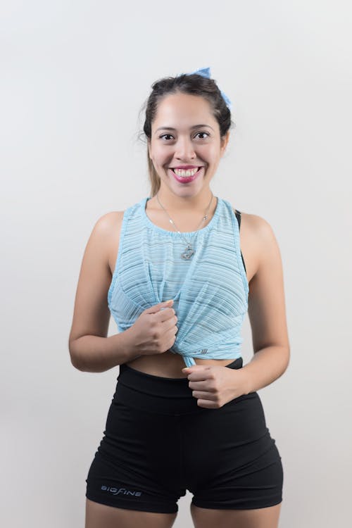 A Woman Tying Her Tank Top while Wearing a Cycling Shorts