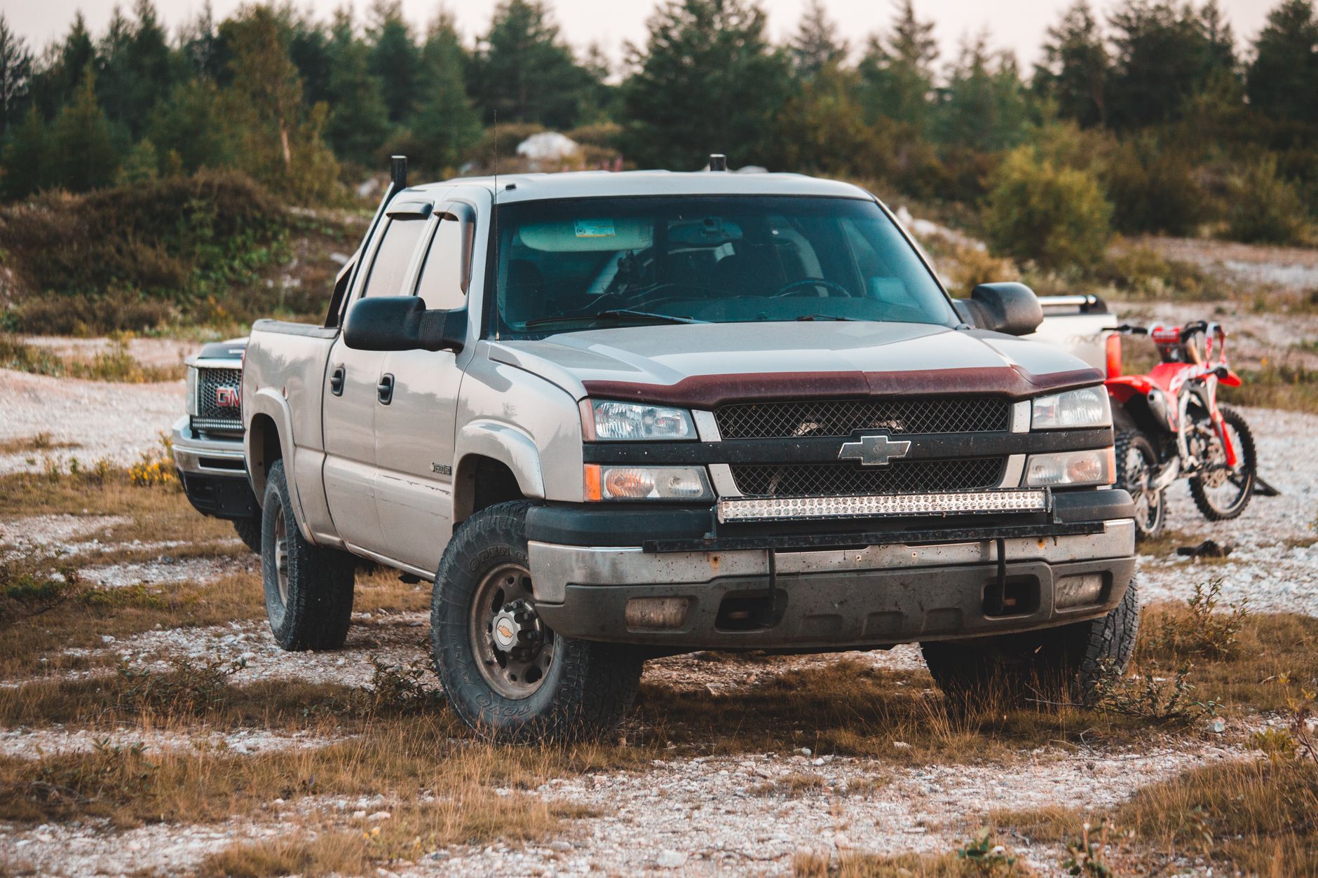 A Chevrolet pickup truck parked on a grassy outdoor field, surrounded by nature.