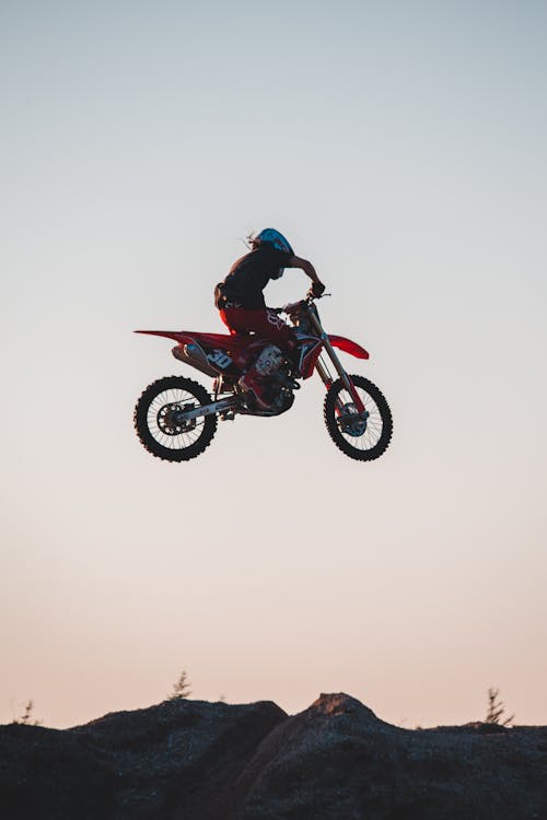 Man Riding a Red Dirt Bike Suspended on the Air