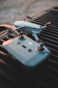 Close-up of DJI Mavic drone and controller on a textured surface at sunset.