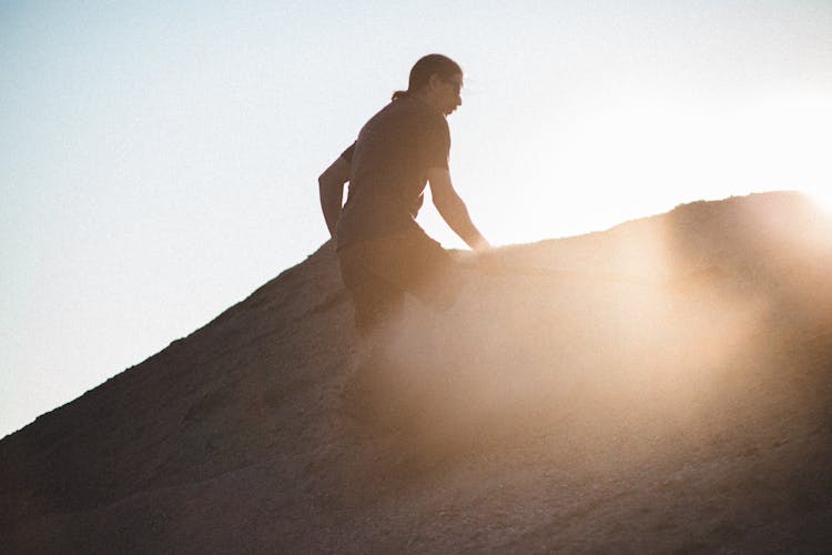 Back Lit Photograph Of A Man Shoveling Sand