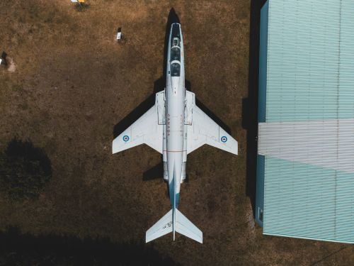 Free Top-down view of a parked jet aircraft beside a hangar on a sunny day. Stock Photo