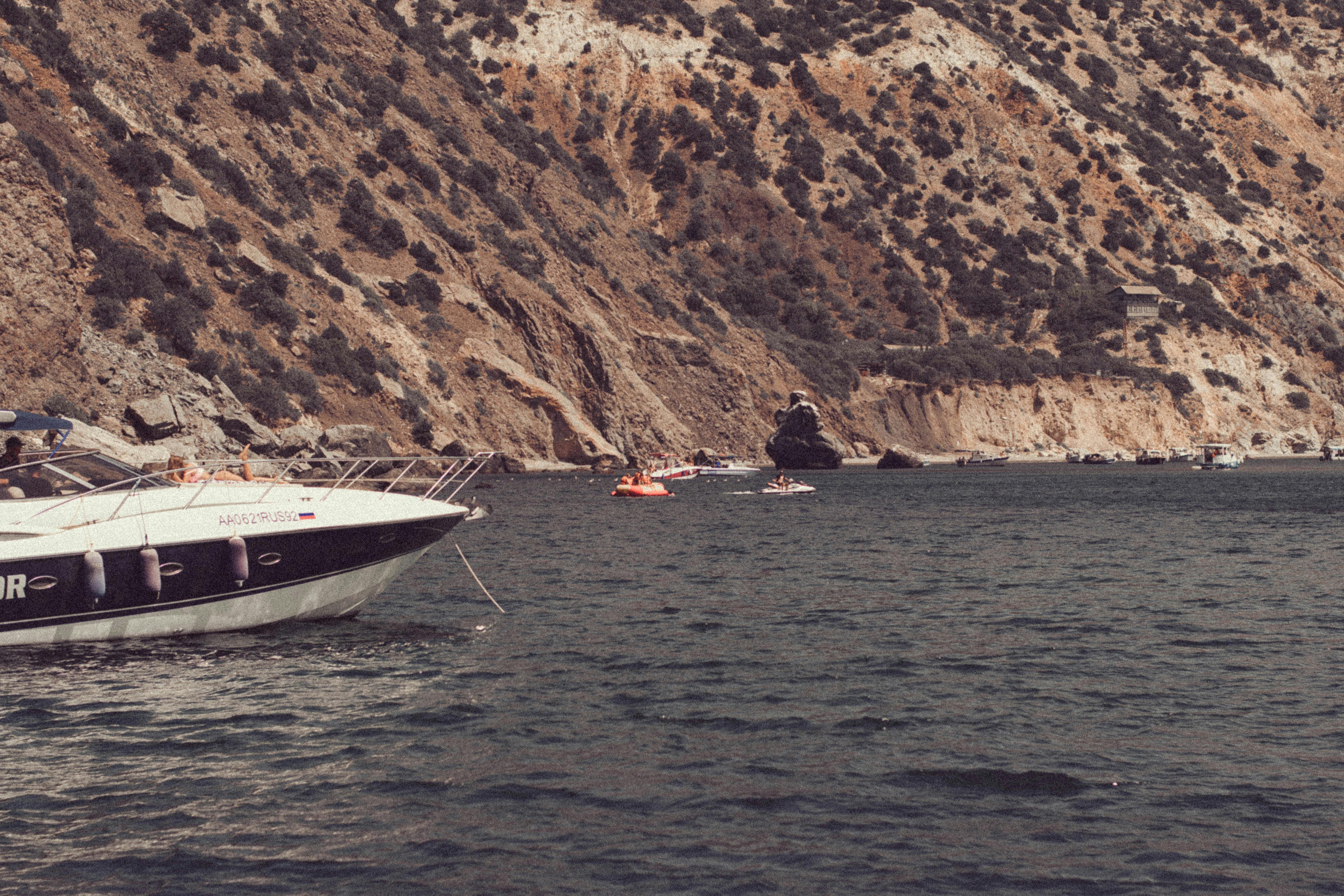 A tranquil coastal scene with boats anchored by rugged cliffs under a clear sky.
