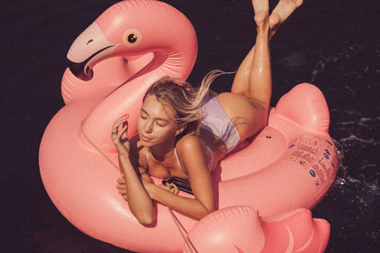 A Woman  Riding A Pink Flamingo Inflatable Floater