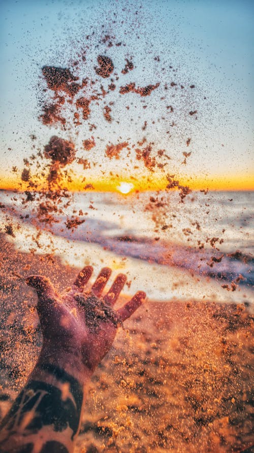 Close Up Photo of a Person Throwing Sand in the Air