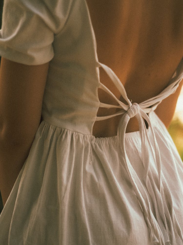 Woman In White Low Back Dress With Ribbon